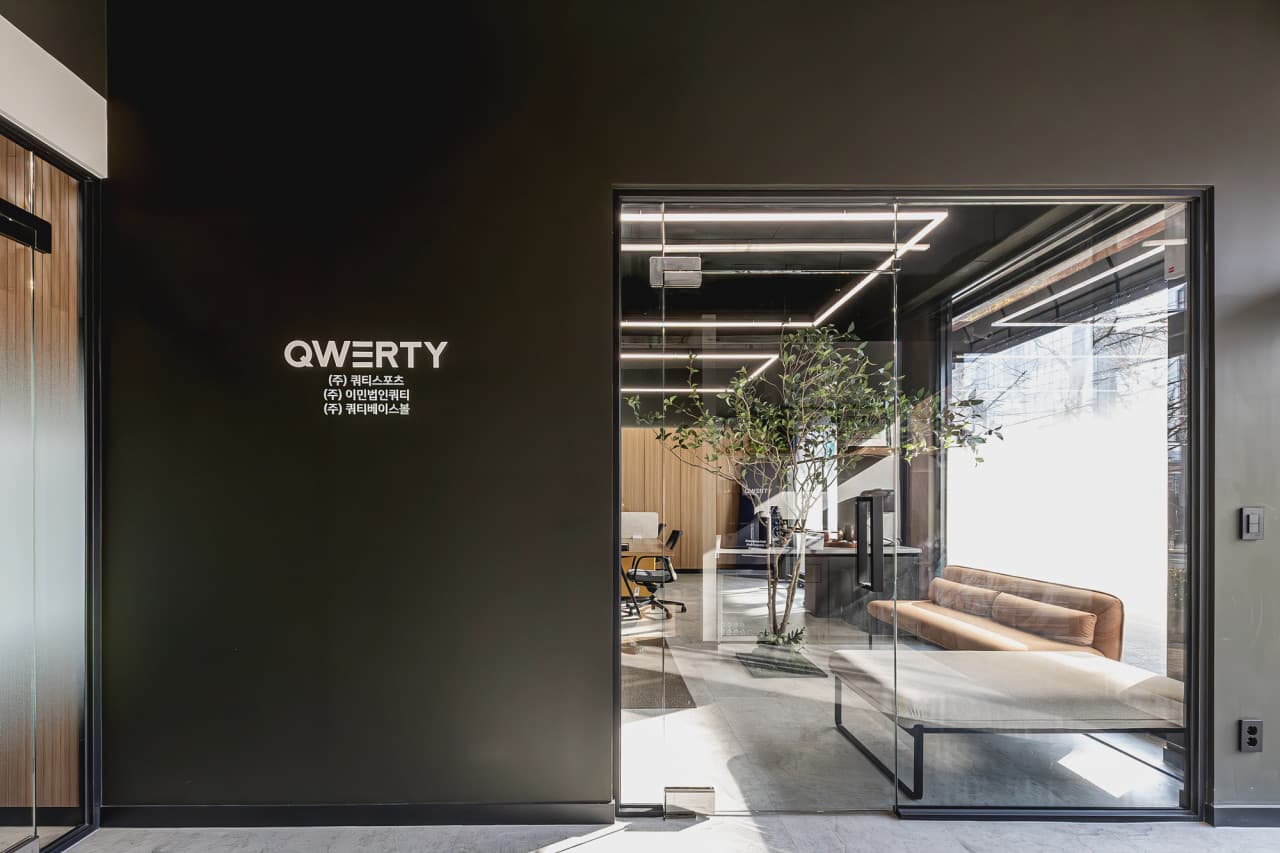 QWERTY 브랜드 벽과 라운지가 보이는 사무실 로비